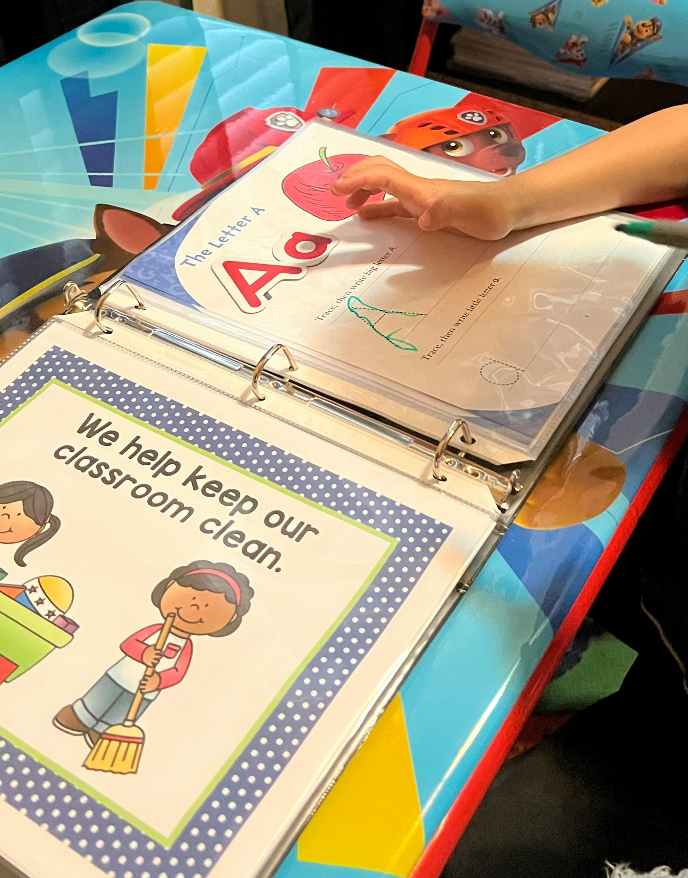 Child's hand touching a binder with educational pages