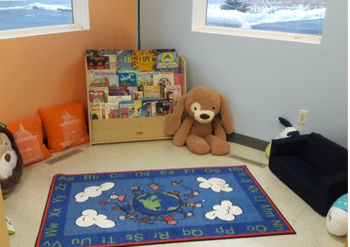 Children's reading corner with a bookshelf, stuffed animals, and a rug