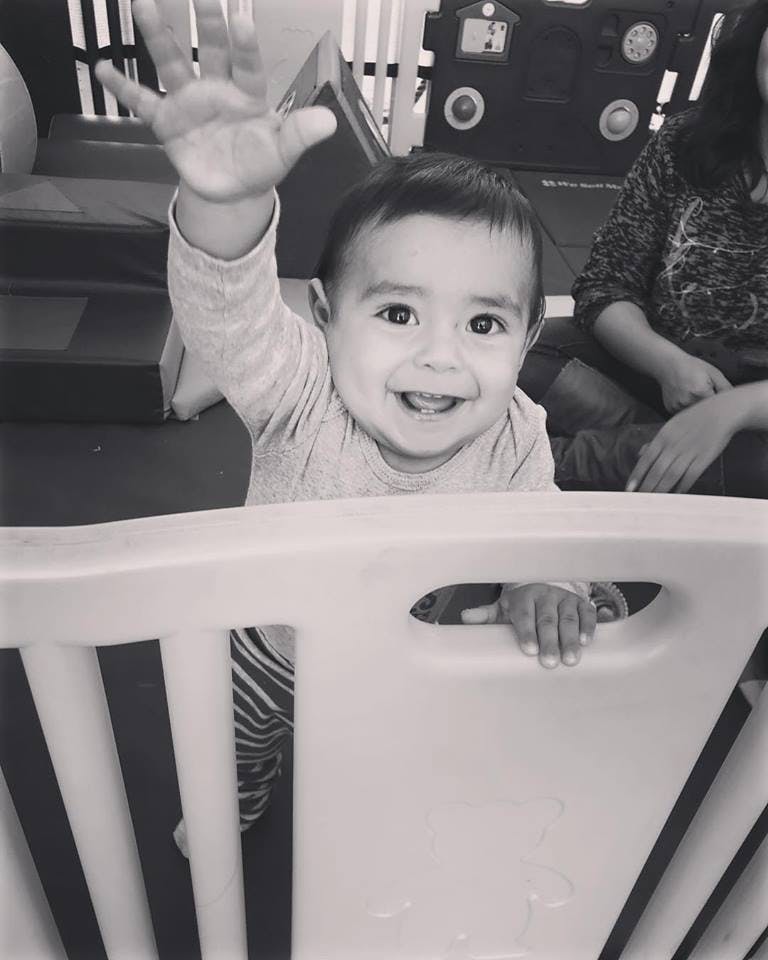 Child waving from behind a barrier