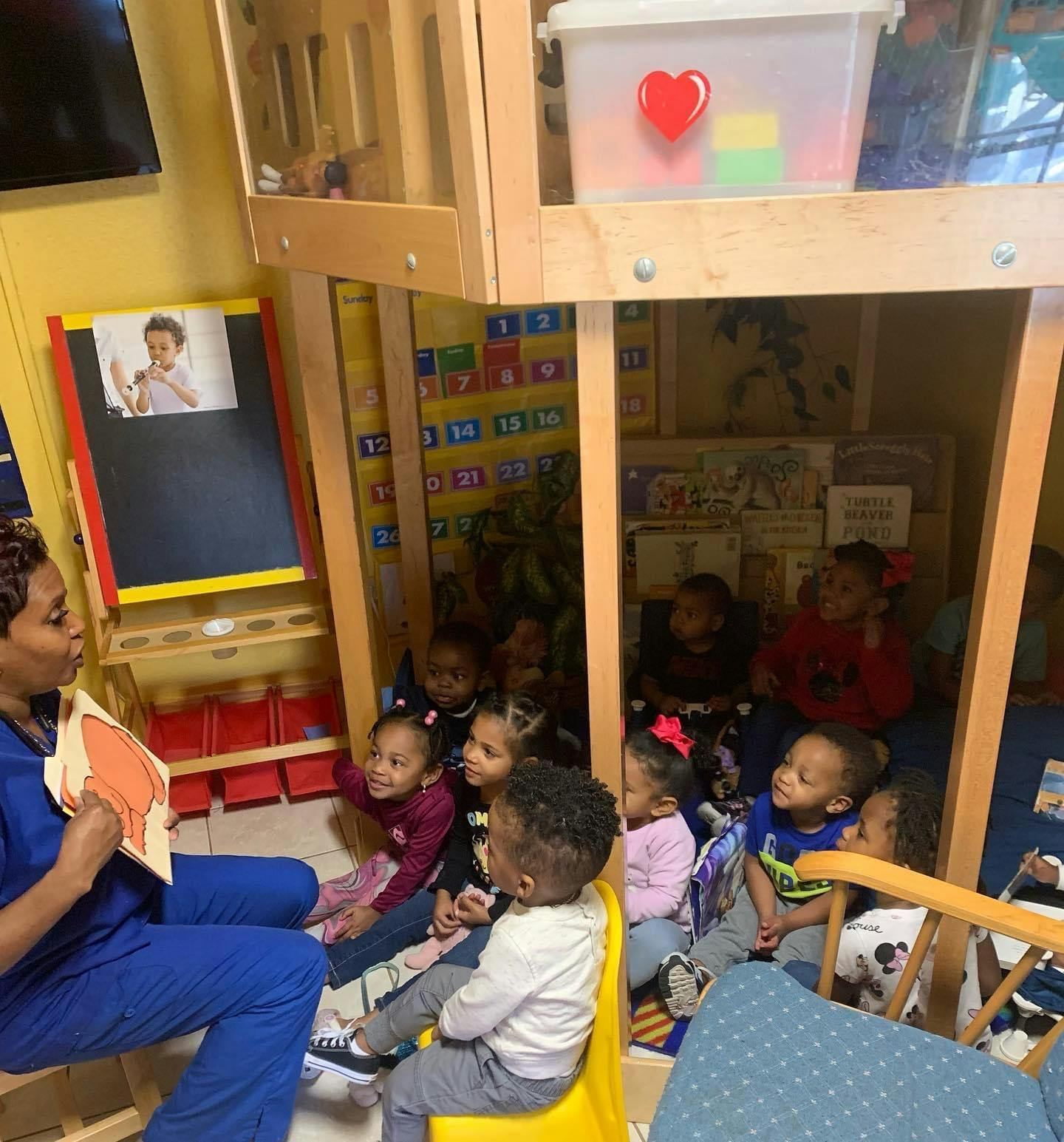 Person reading a book to a group of children in a classroom