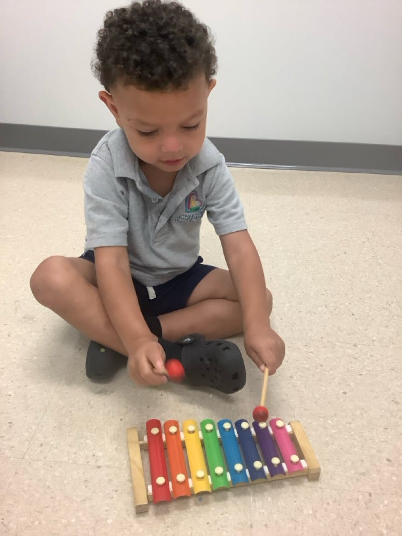 Child playing a colorful xylophone on the floor