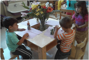 Three children drawing at a table