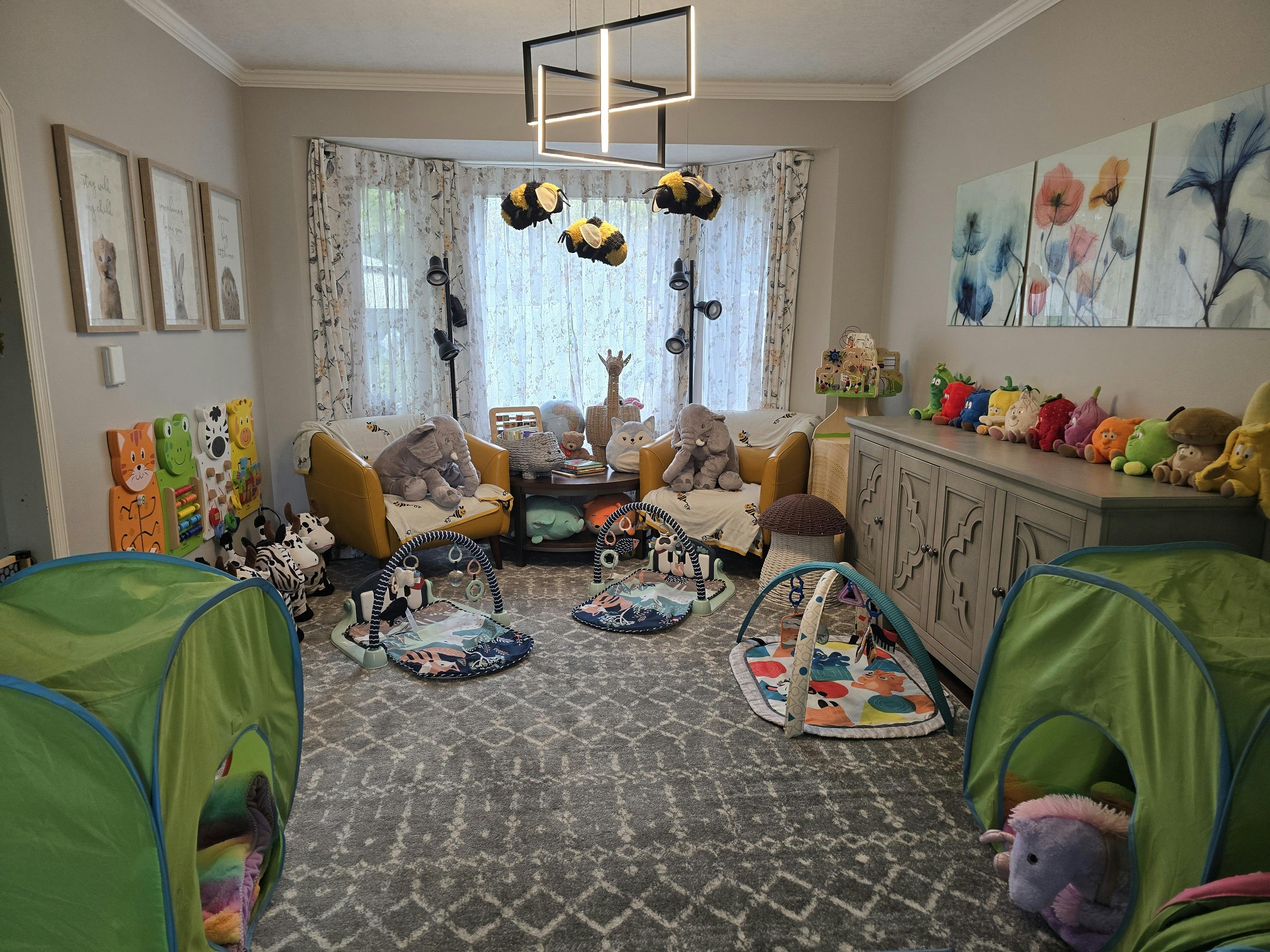 Playroom with two green tents, baby activity mats, and stuffed animals