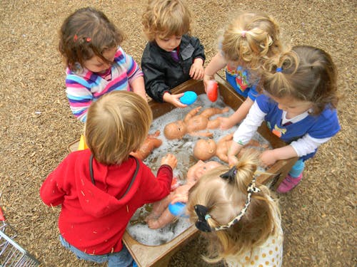 Children playing with dolls in a water table