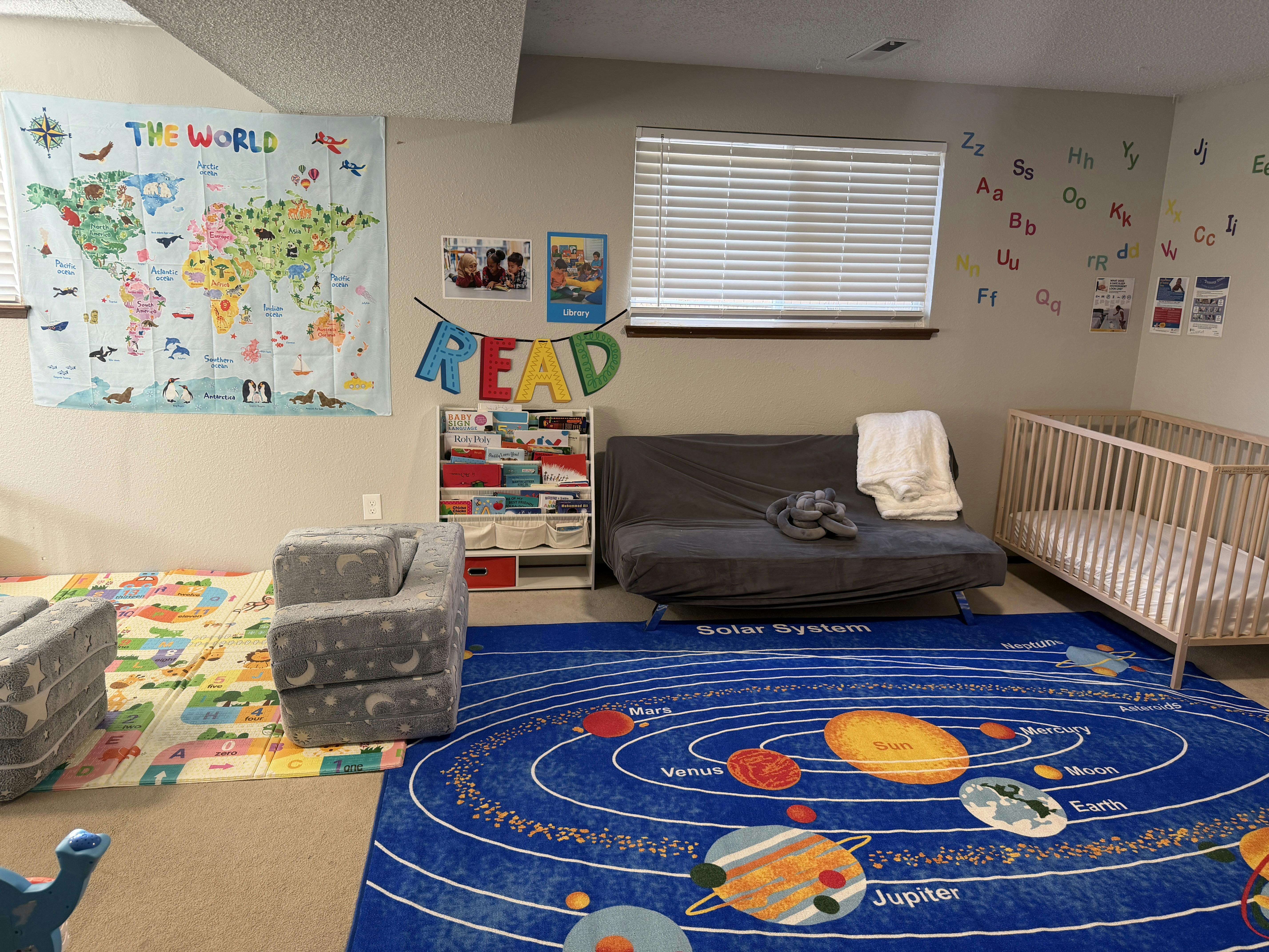 Childcare room with a solar system rug, crib, reading nook, and world map