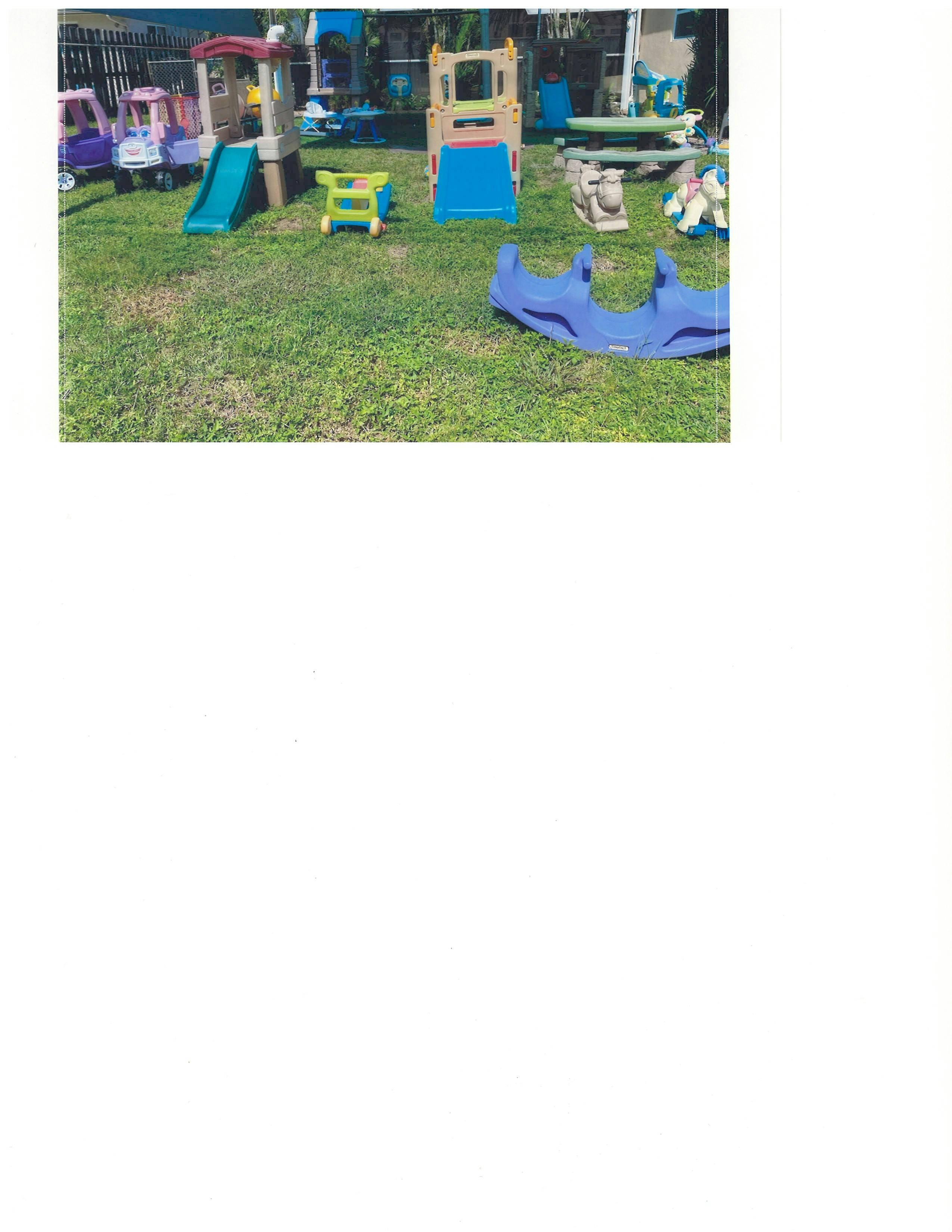 Outdoor playground with slides, playhouses, and a blue seesaw on grass