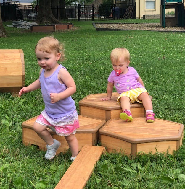 Two children playing on wooden blocks in grass