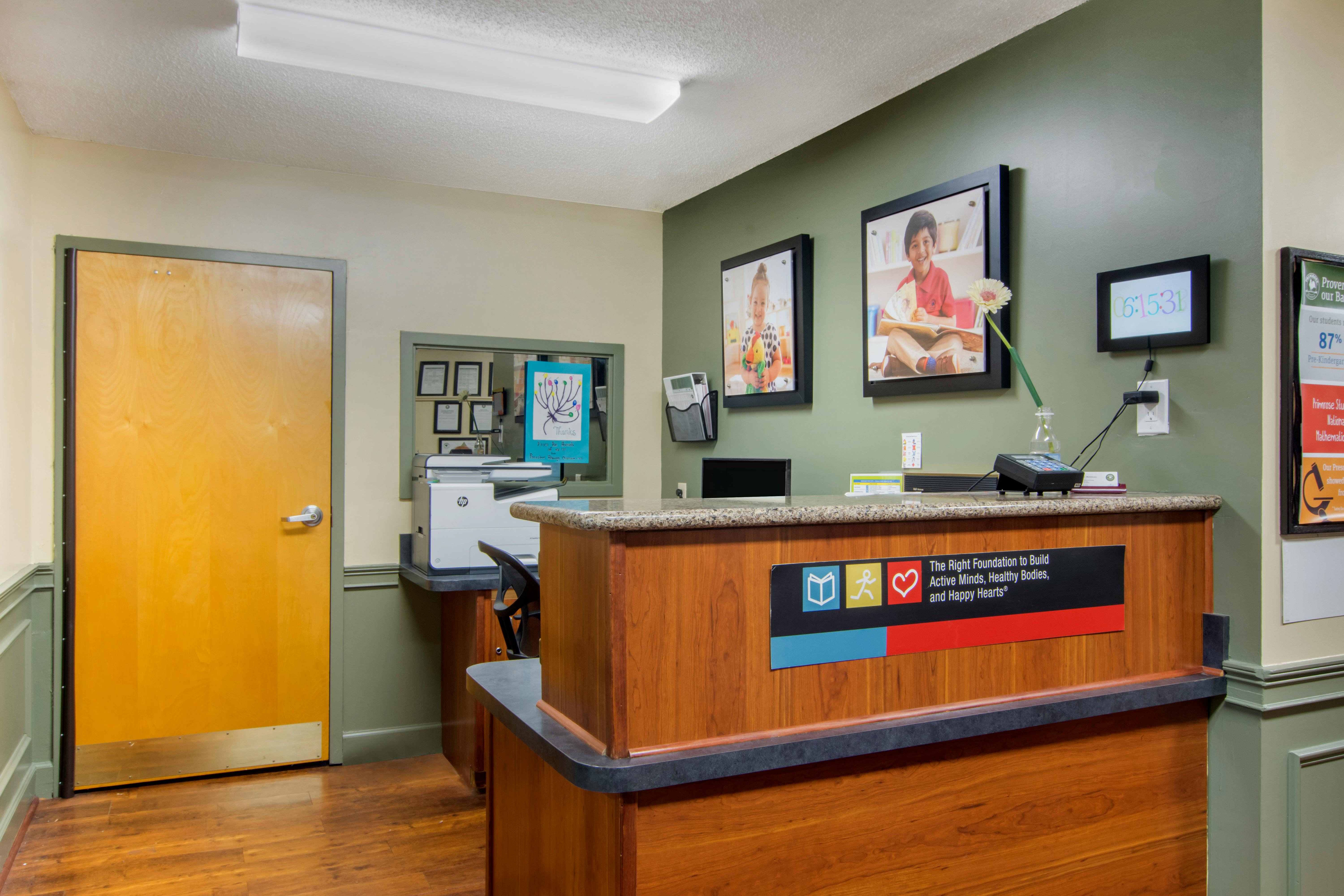 Reception desk with wood and granite, two framed photos of children, and a printer
