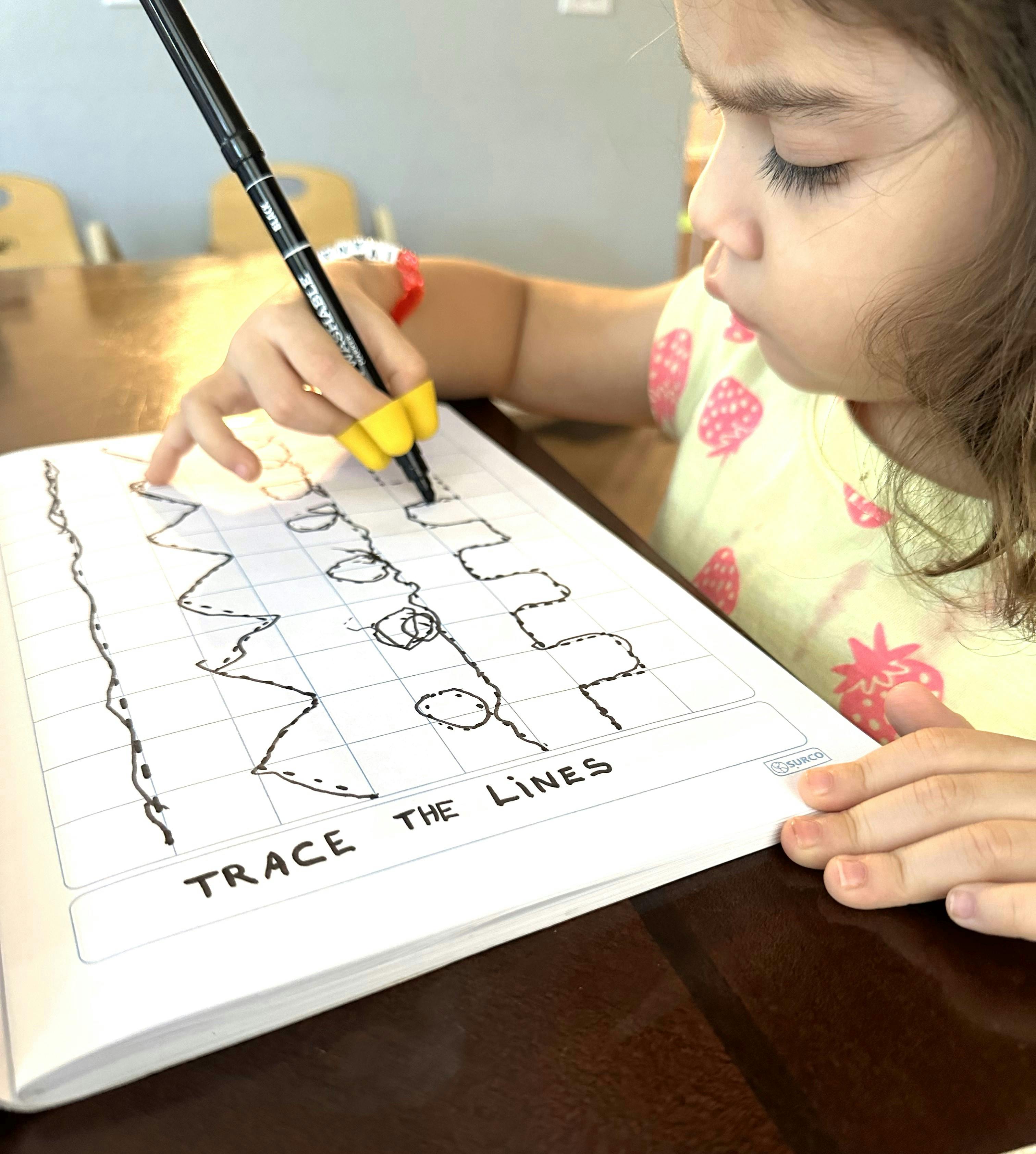 Child tracing lines on paper with a pen