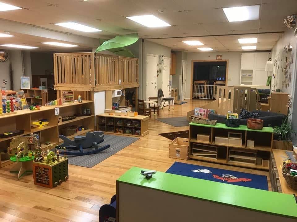 Classroom with wooden play structure, shelves, and various toys