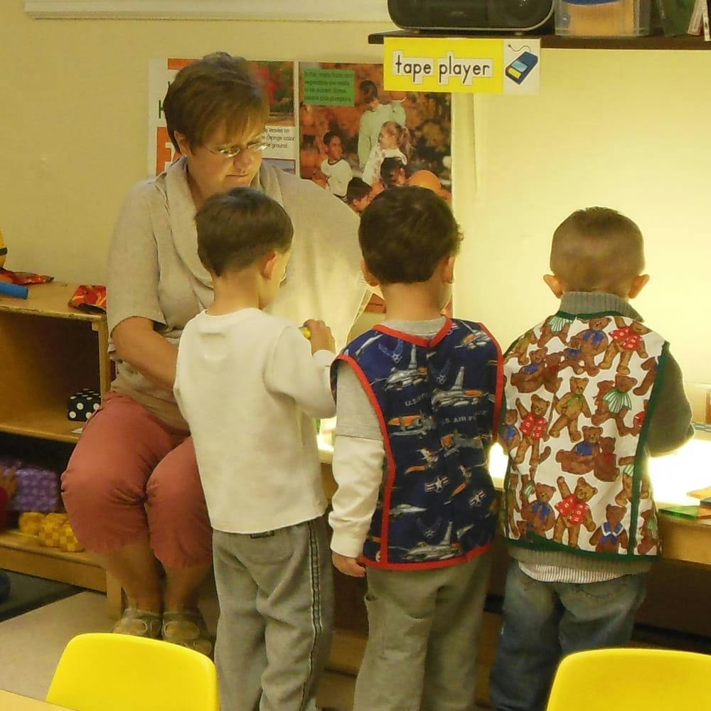 Adult person sitting with three children standing in front of them