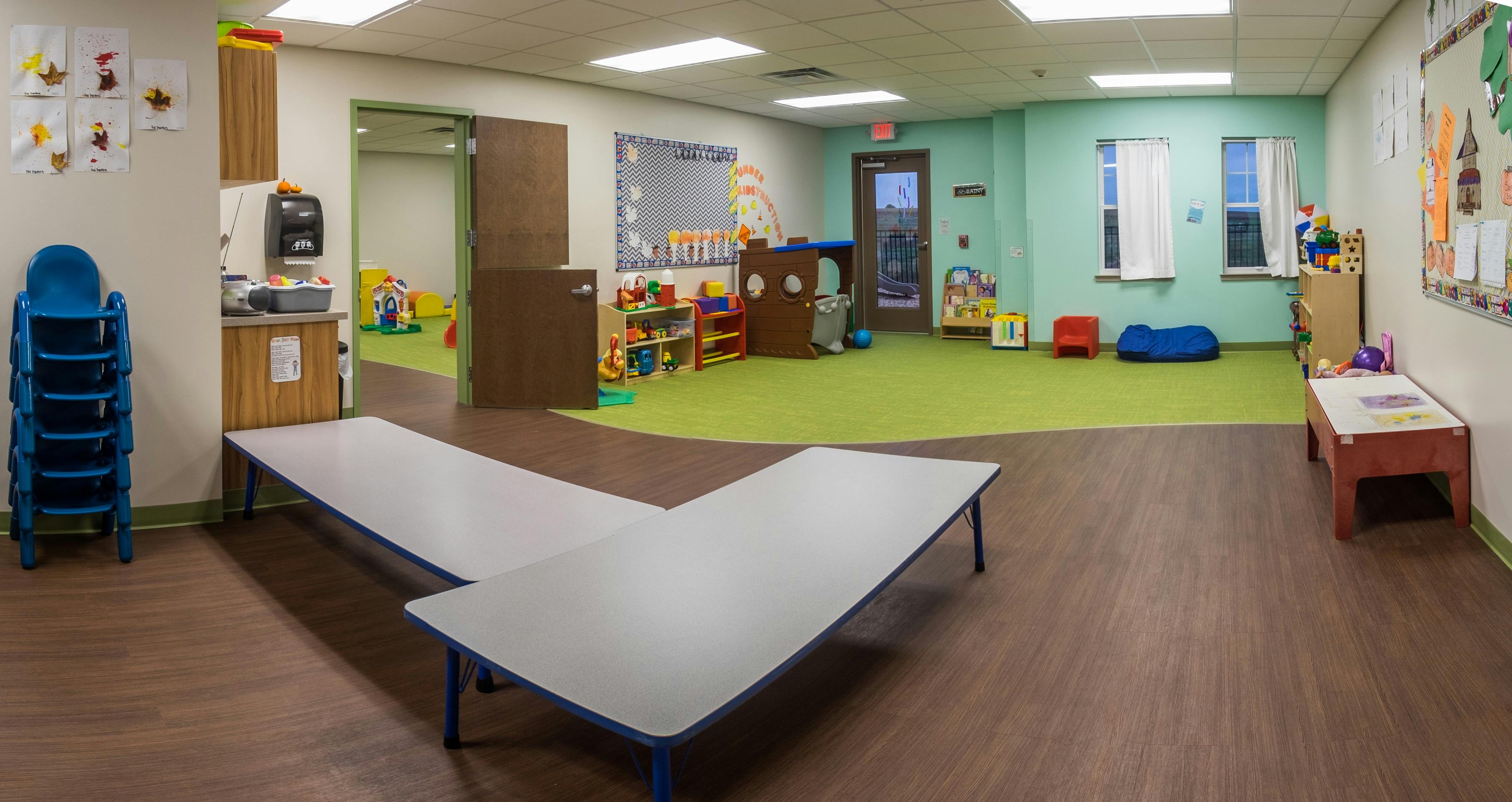 Empty classroom with tables, chairs, and play areas