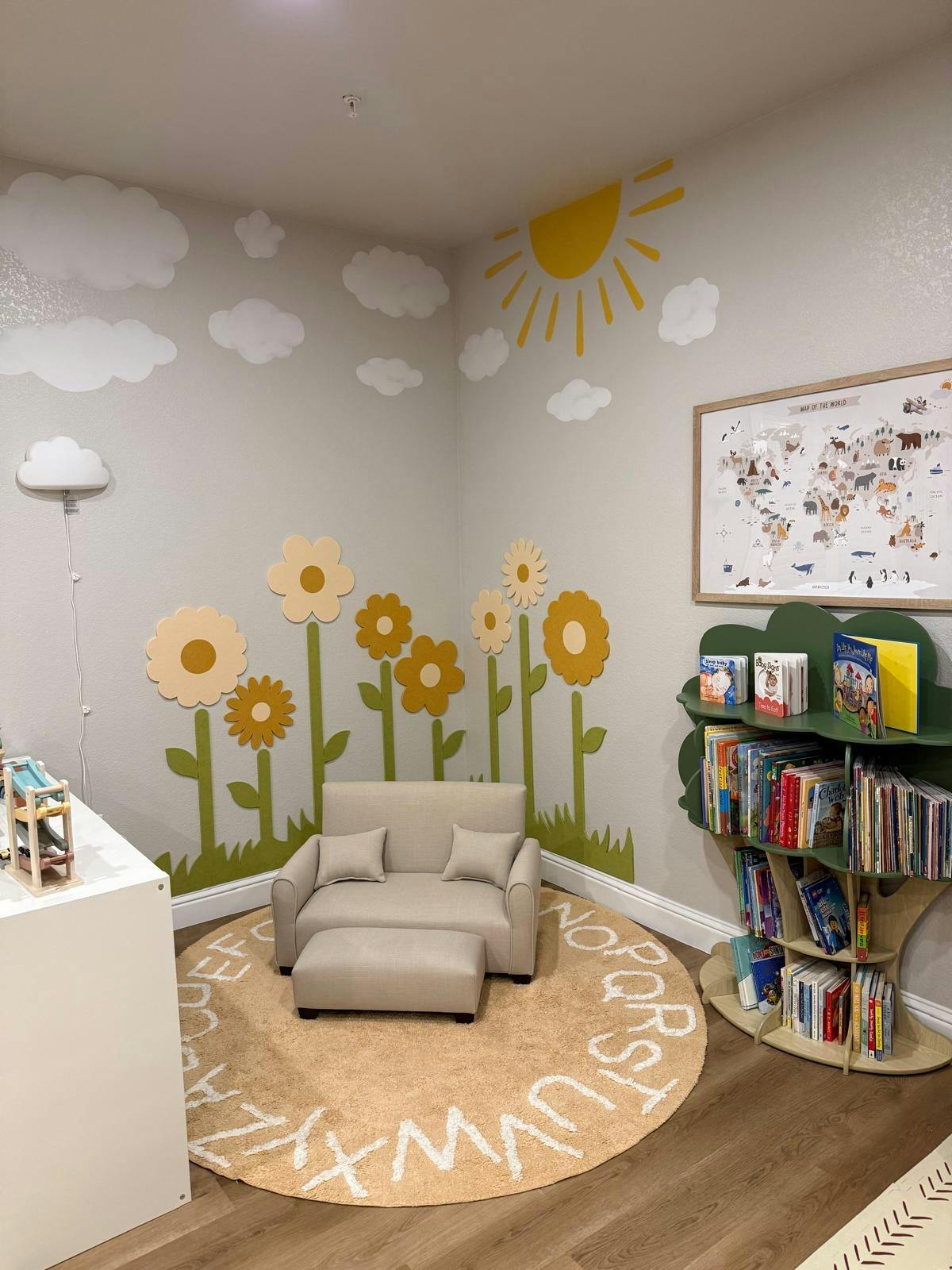 Children's room with a small couch, tree-shaped bookshelf, and wall decals