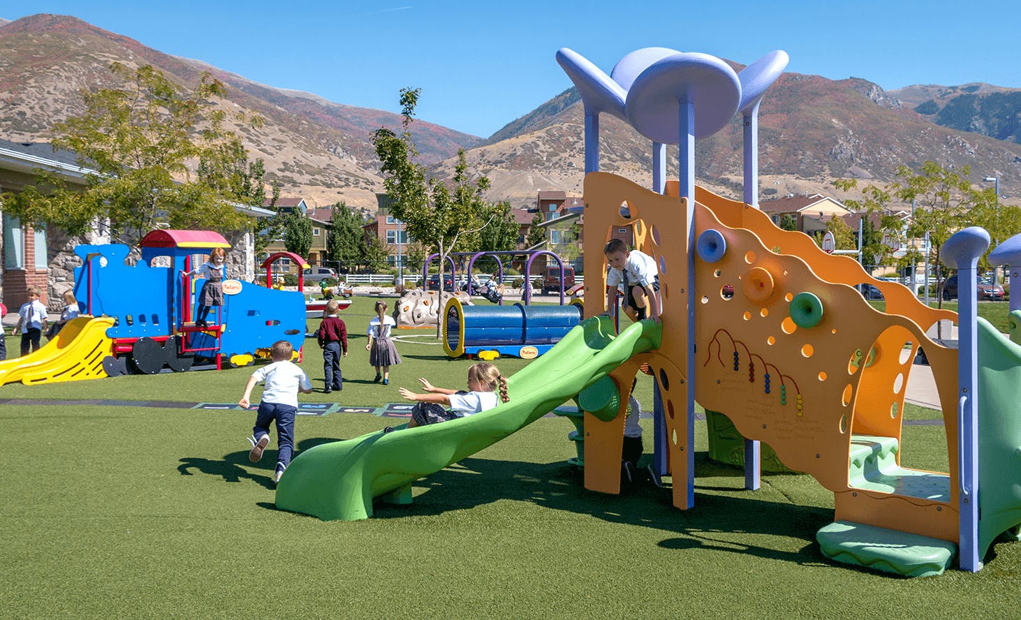 Children playing on a playground with slides and a train structure