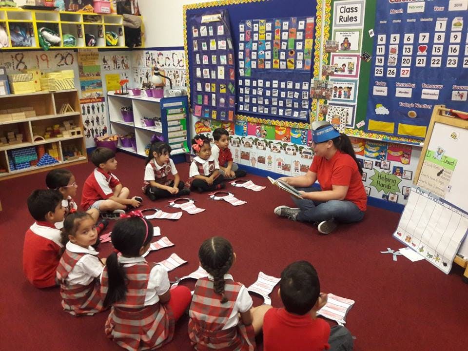 Person reading to children sitting in a circle on the floor in a classroom