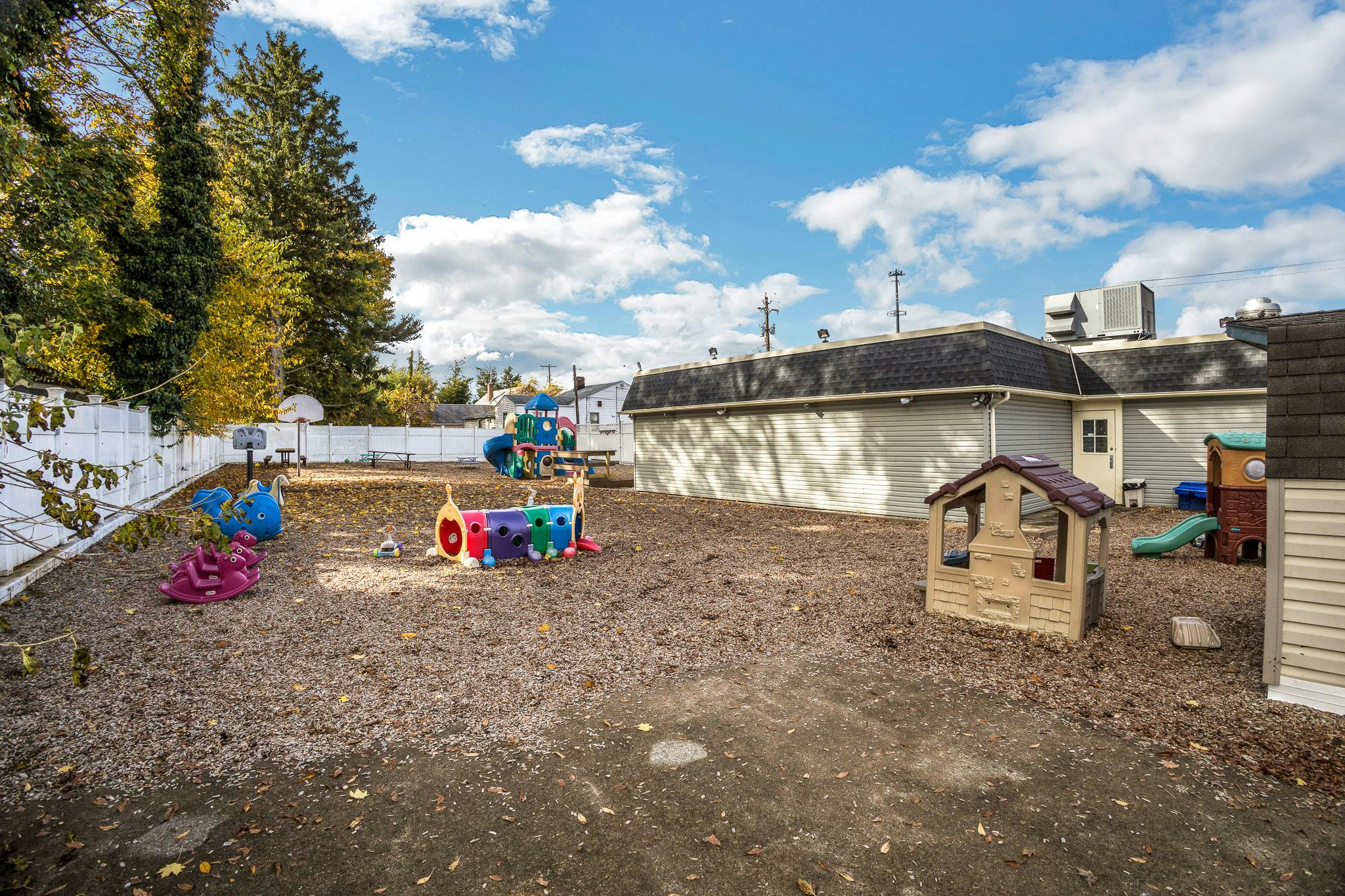 Outdoor playground with various colorful play structures and fall leaves on the ground
