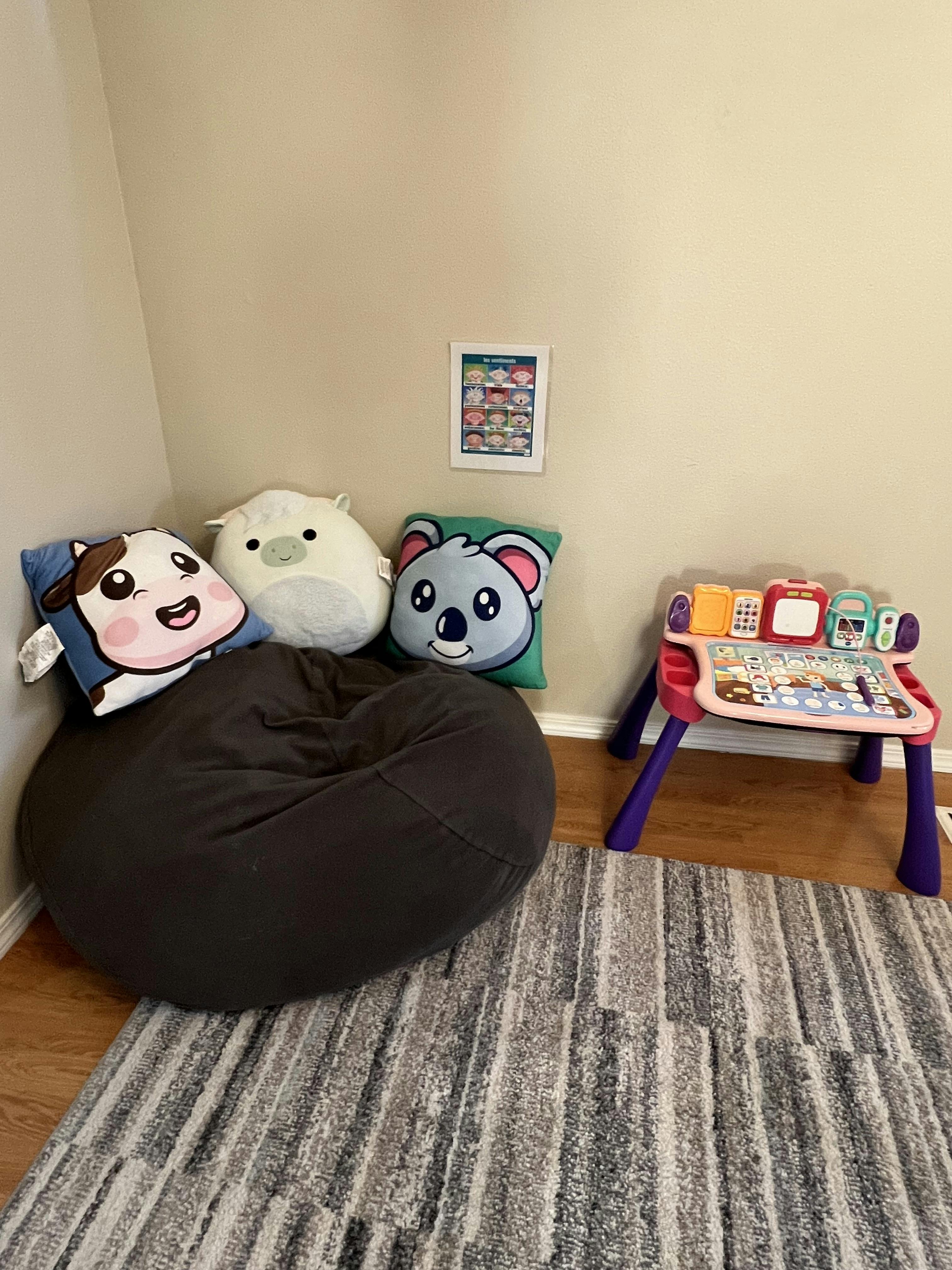 A bean bag chair with stuffed animal pillows and a child's activity table