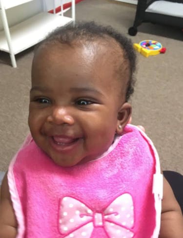Smiling baby wearing a pink bib with a bow