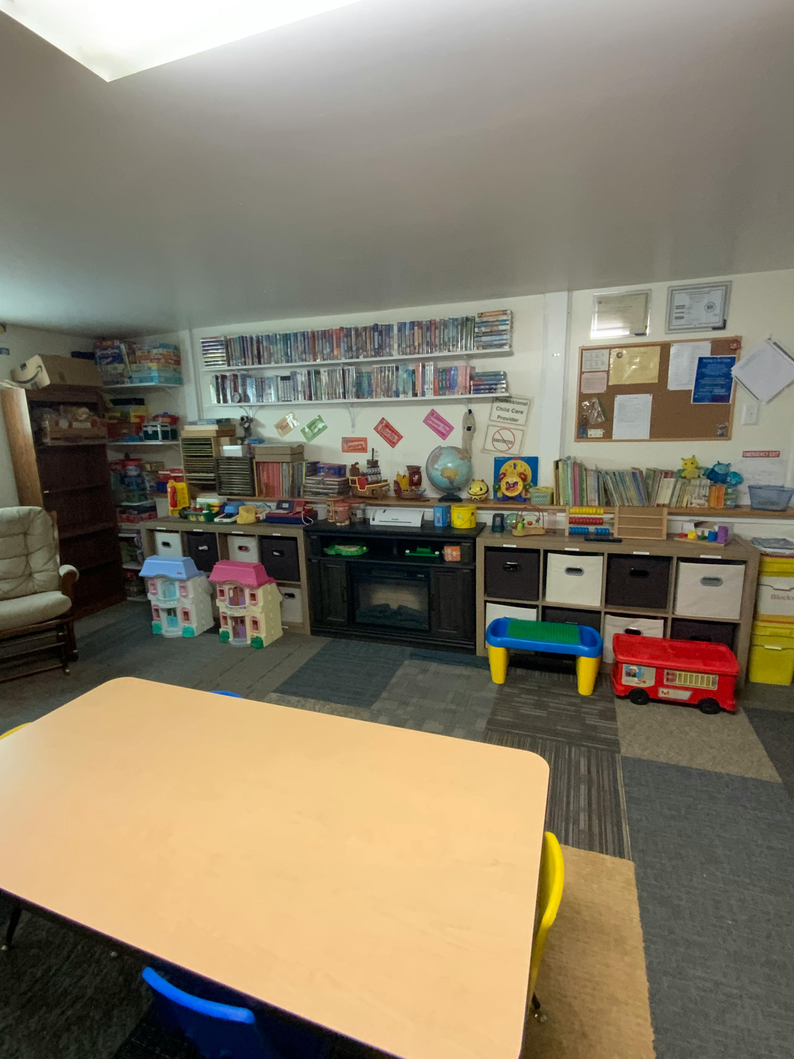 Classroom with a table, shelves of books, and toys