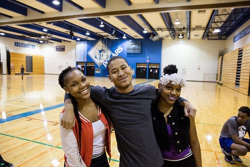 Three teens posing for a photo in a gymnasium