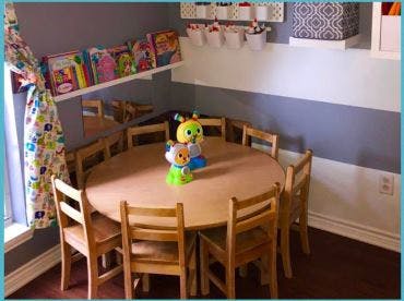 Small wooden table and chairs in a classroom with a toy on the table