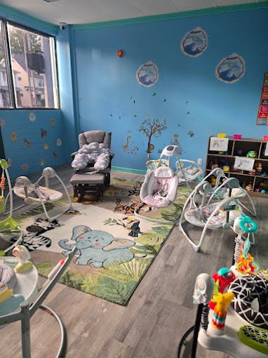 Infant room with multiple baby swings and bouncers on a rug
