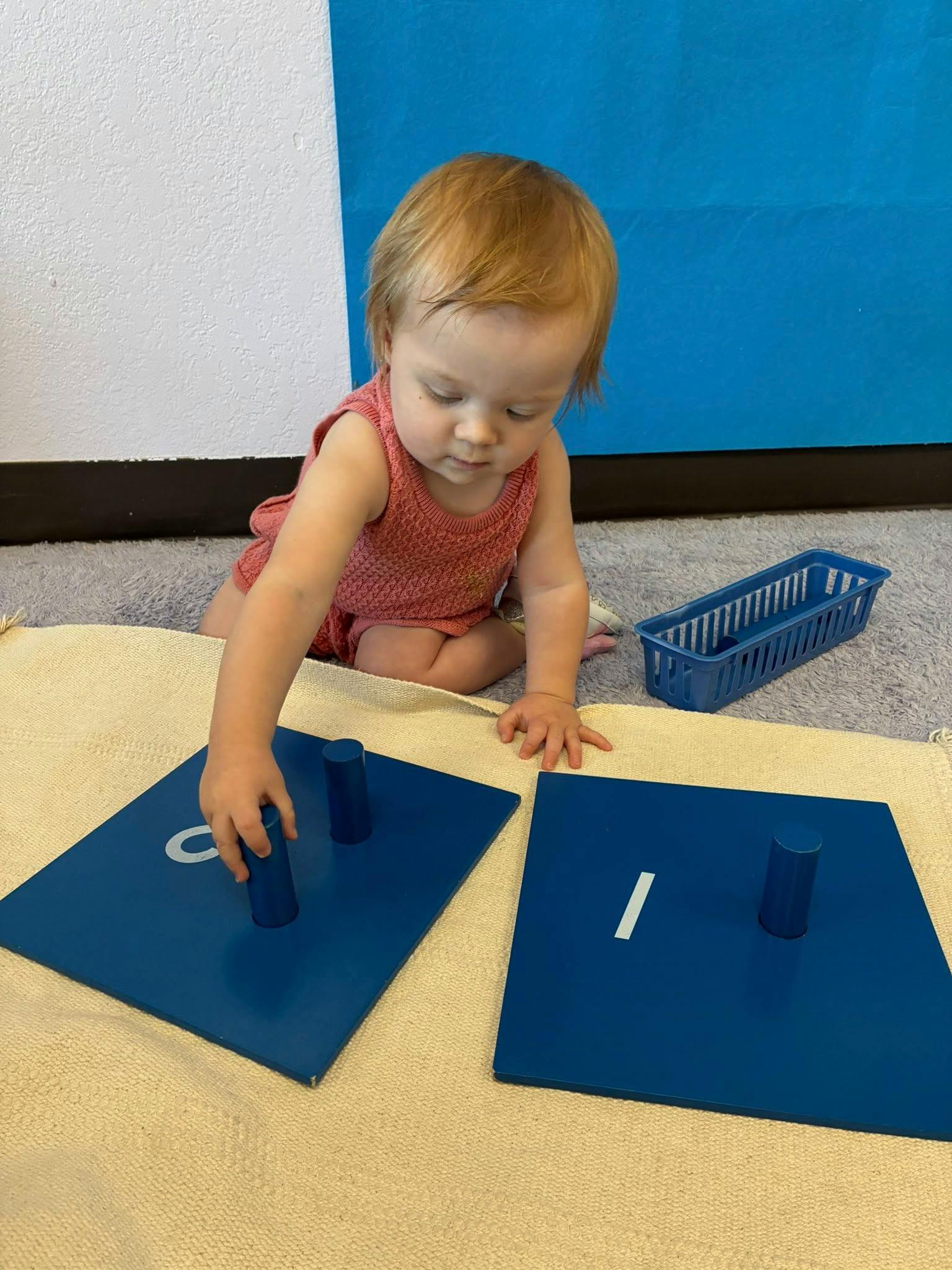 Child playing with blue cylinder blocks on a mat