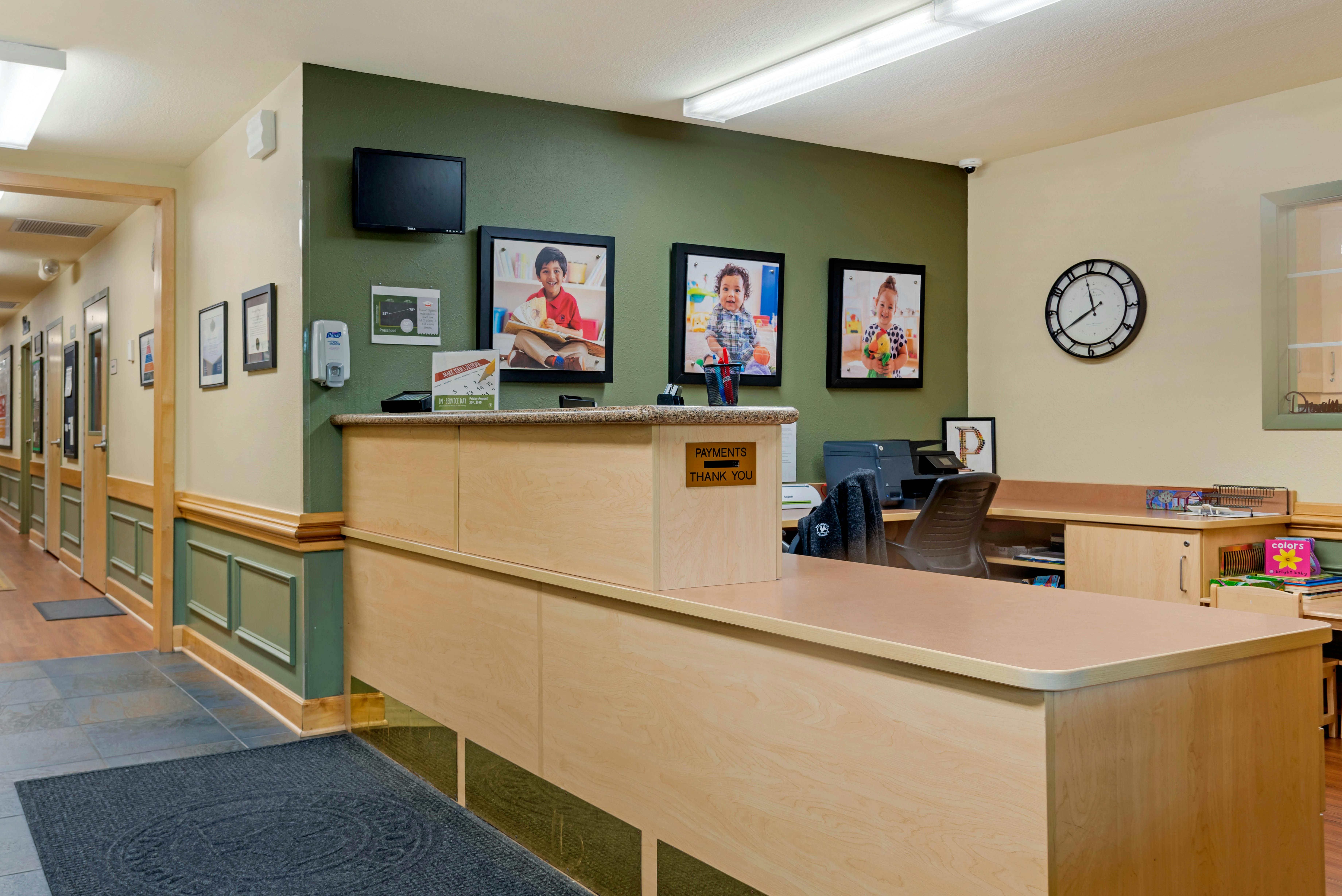 Reception desk in an office with photos of children on the wall