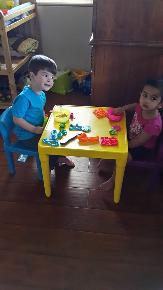 Two children playing with toys at a yellow table