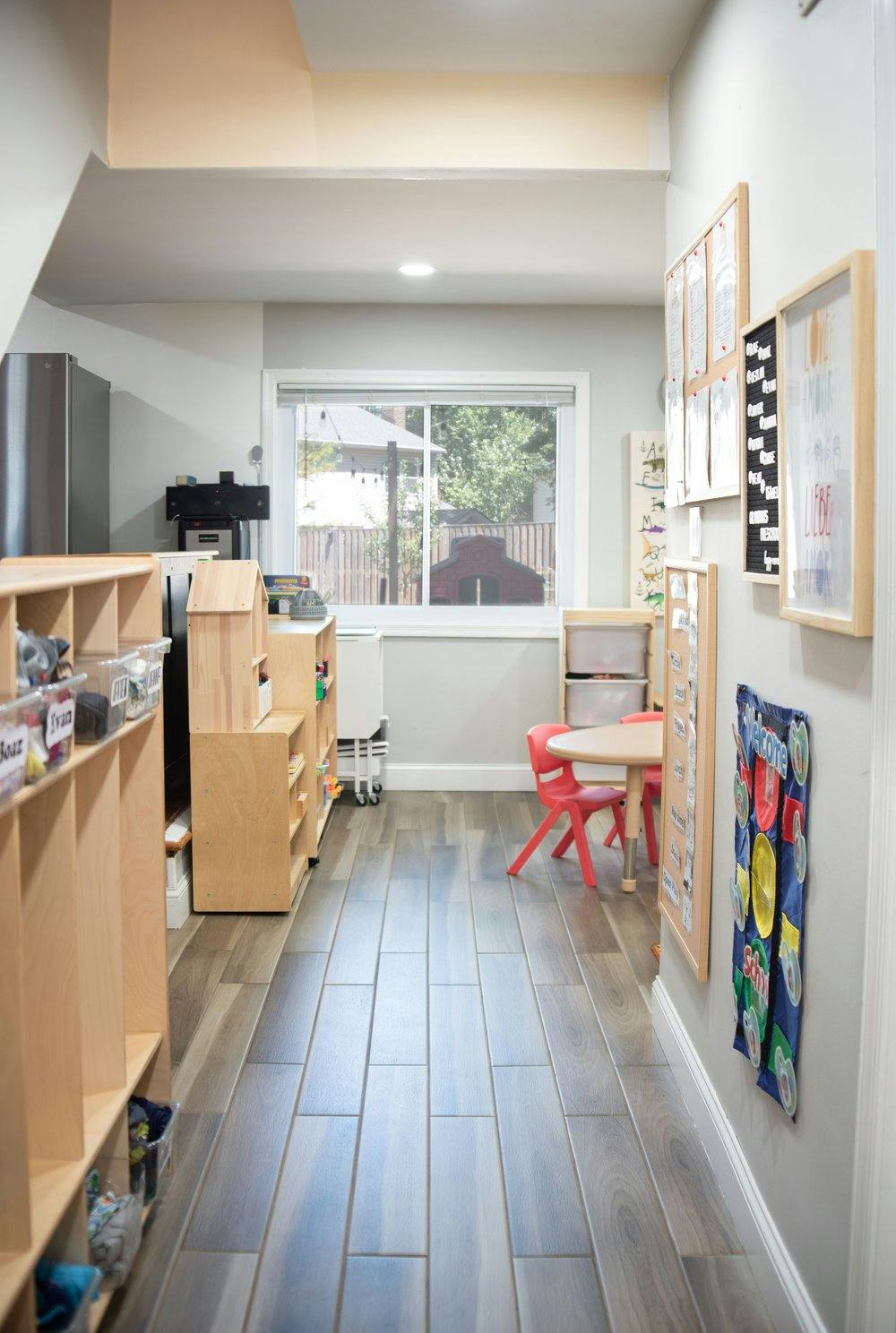 Hallway with wooden shelves, a window, and a small table with red chairs
