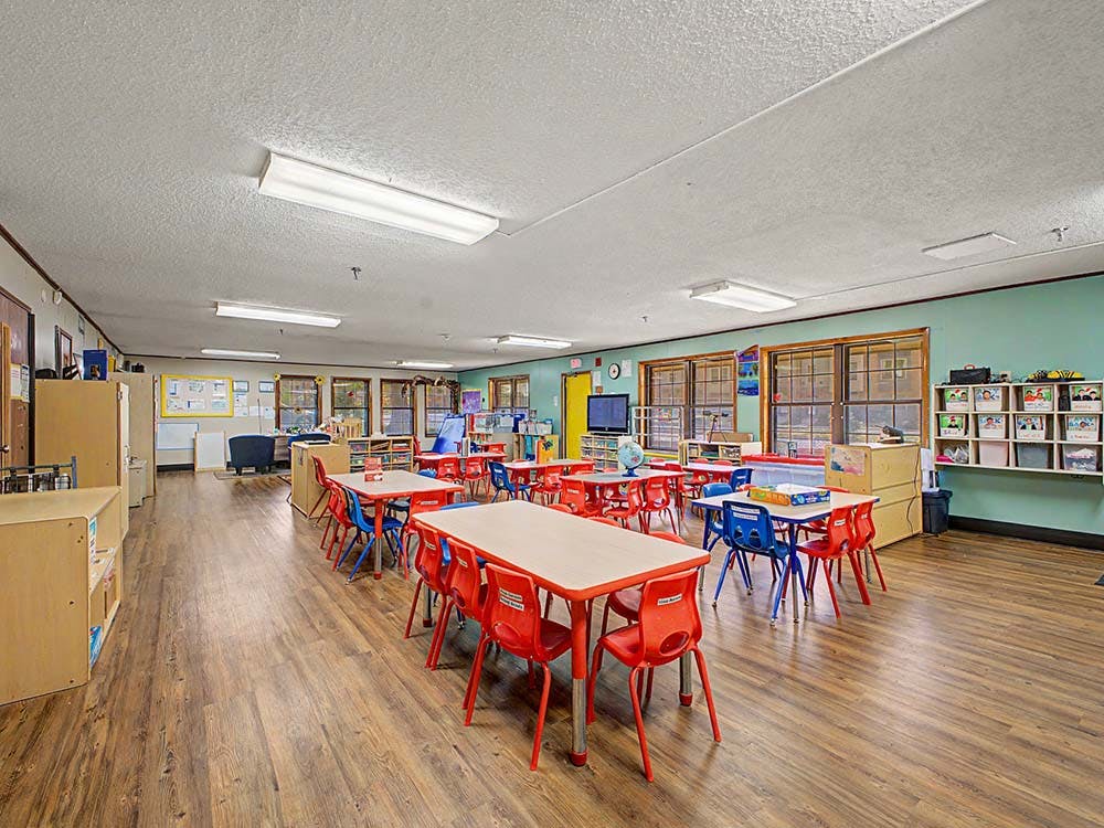 Empty classroom with small red and blue chairs and tables