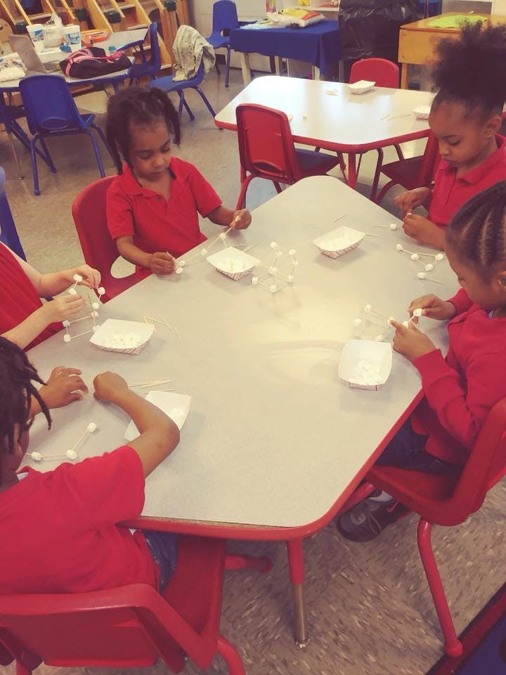 Children at a table doing an activity with small white objects