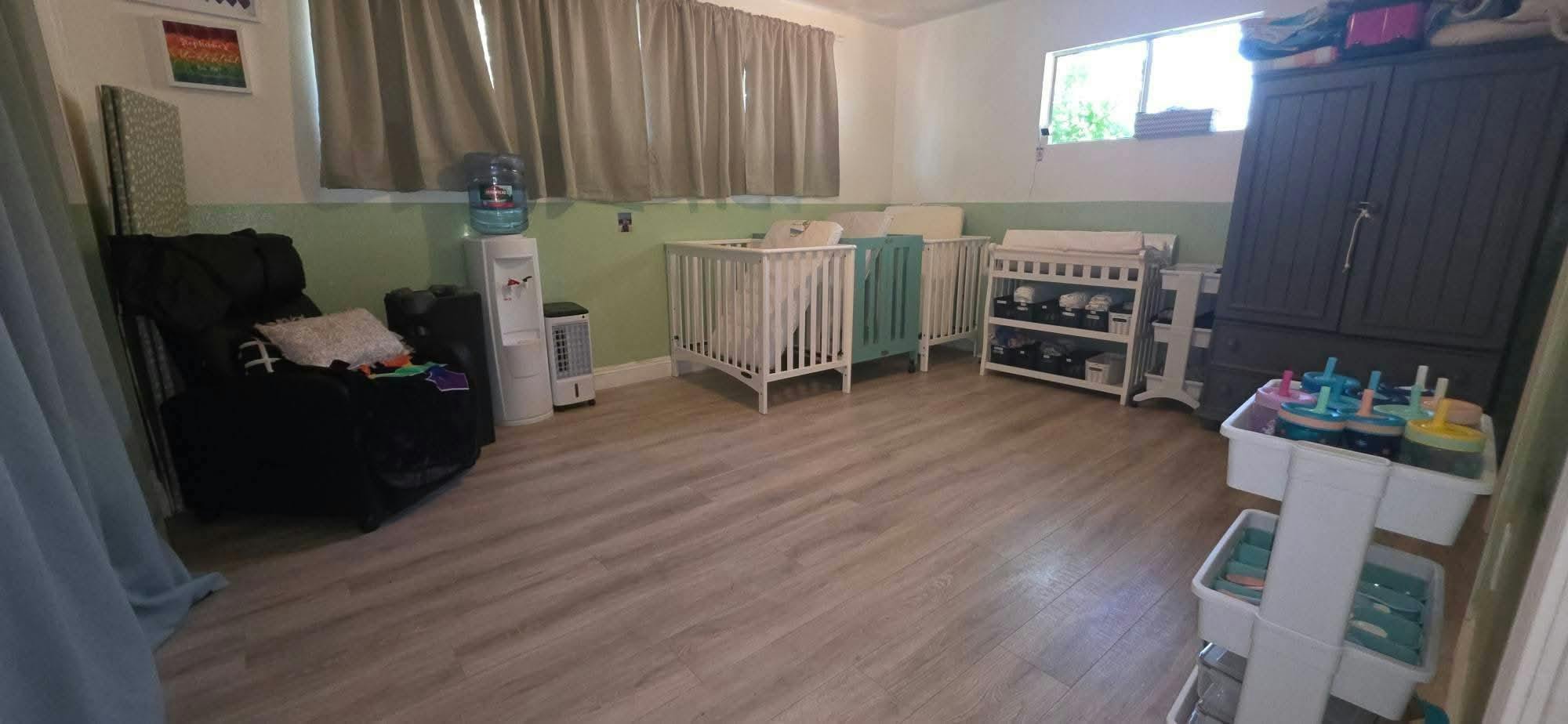Nursery featuring two cribs a changing table a recliner and storage