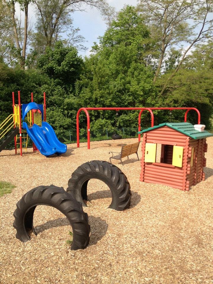 Playground with slide, swing set, playhouse, and tire arches