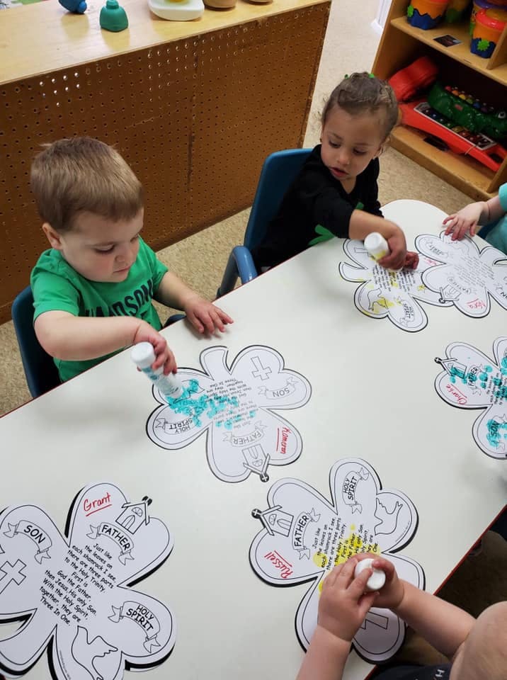 Two children at a table coloring clover-shaped papers