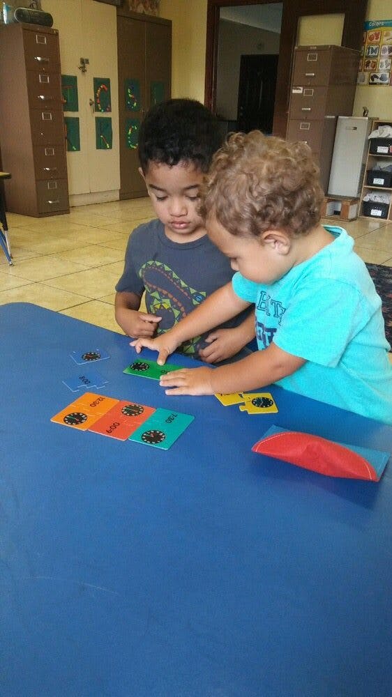 Two children playing with colorful cards on a blue table