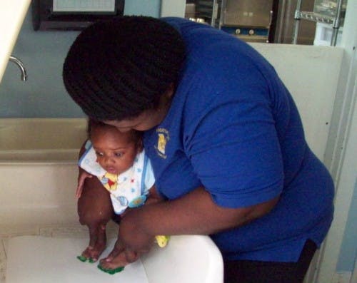 Person holding a child over a sink