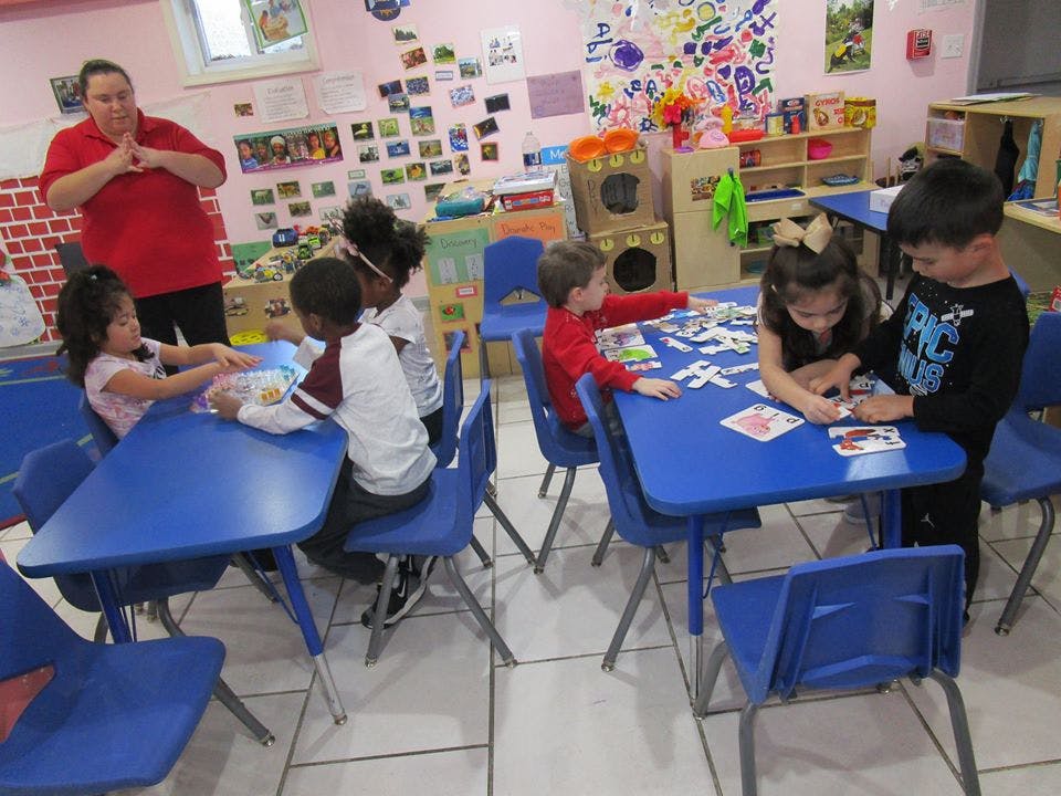 Adult and children at tables in a classroom