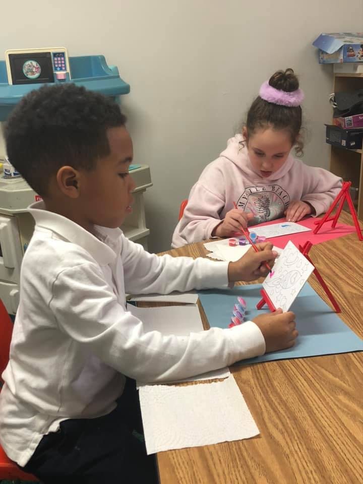 Two children drawing at a table in a classroom