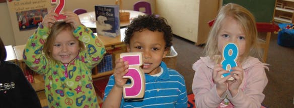 Three children holding up numbers