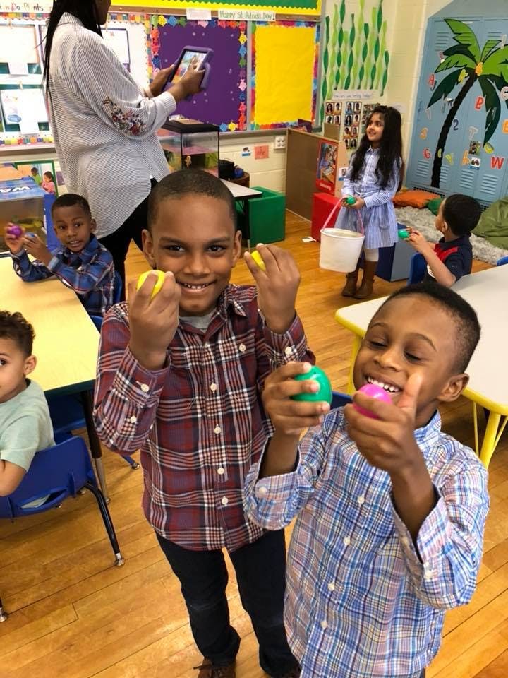 Two children holding colorful plastic eggs in a classroom