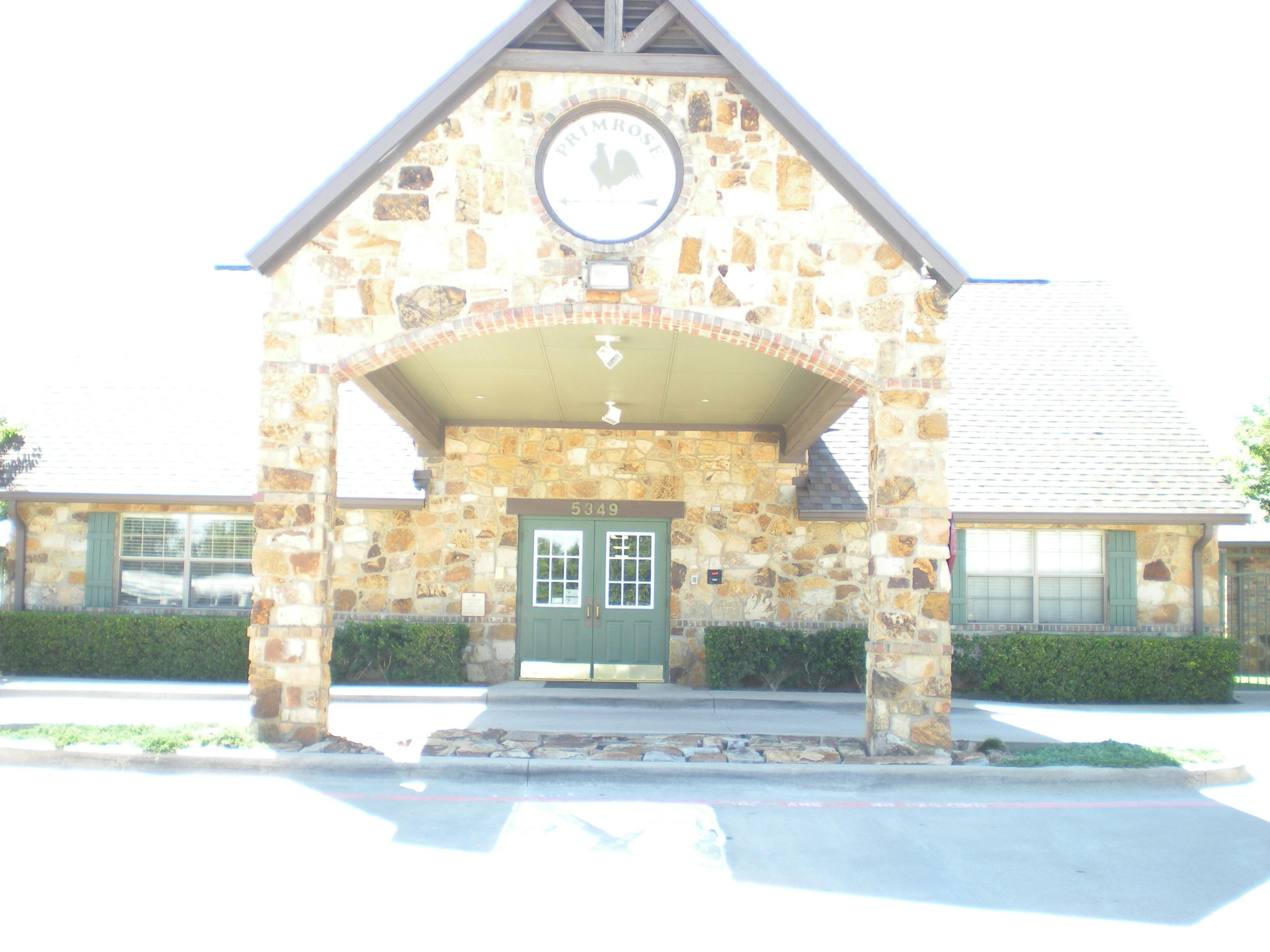 Stone building with a covered entrance and green double doors