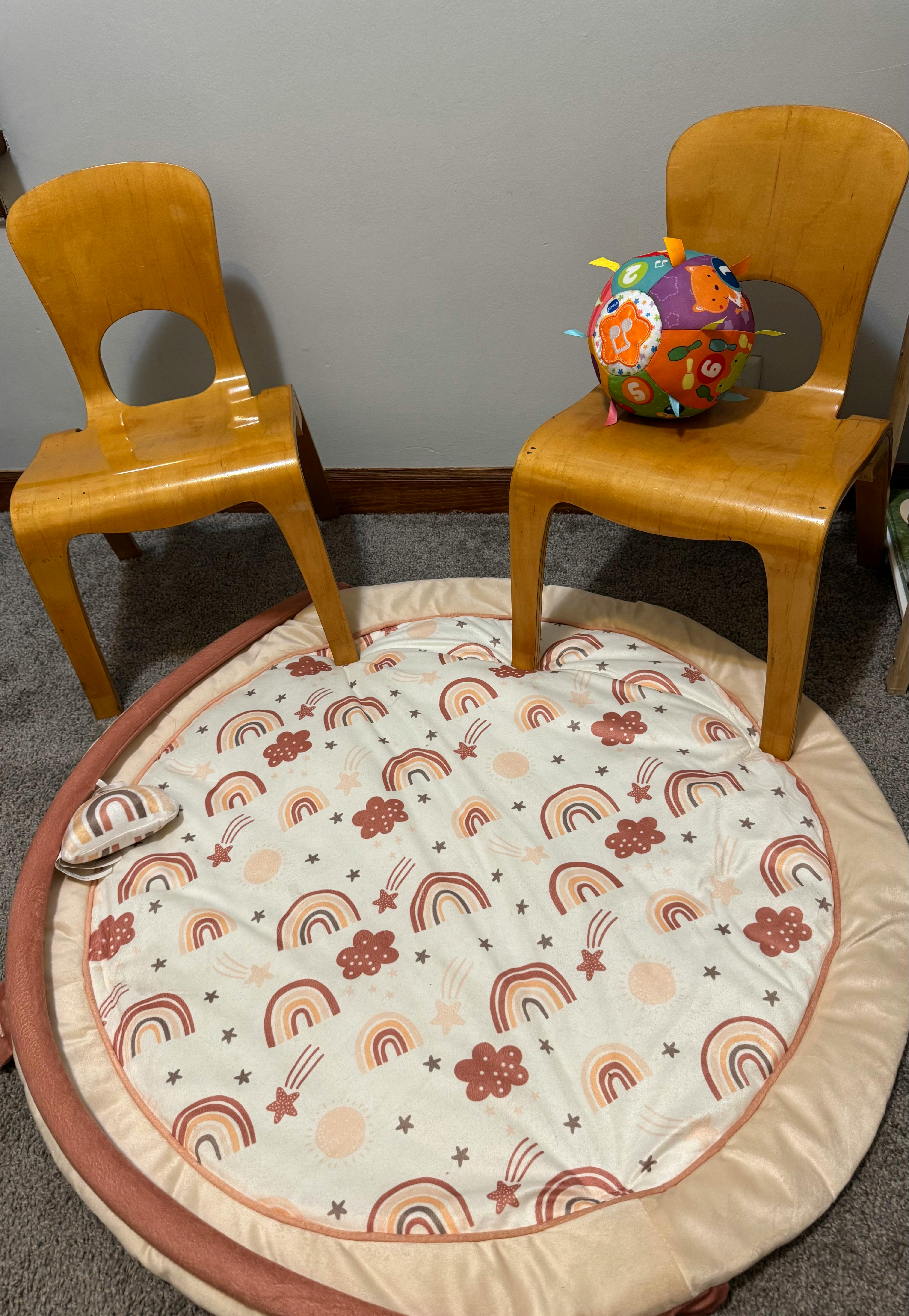 Two wooden chairs with a round playmat on the floor