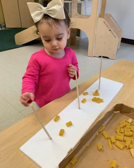 Child playing with pasta and sticks on a table