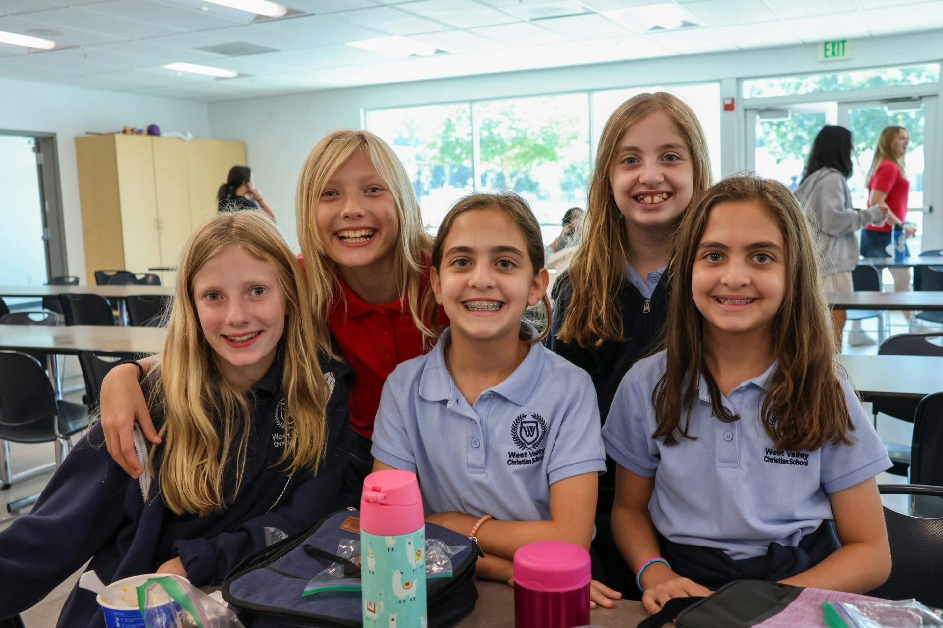 Five children smiling in a classroom