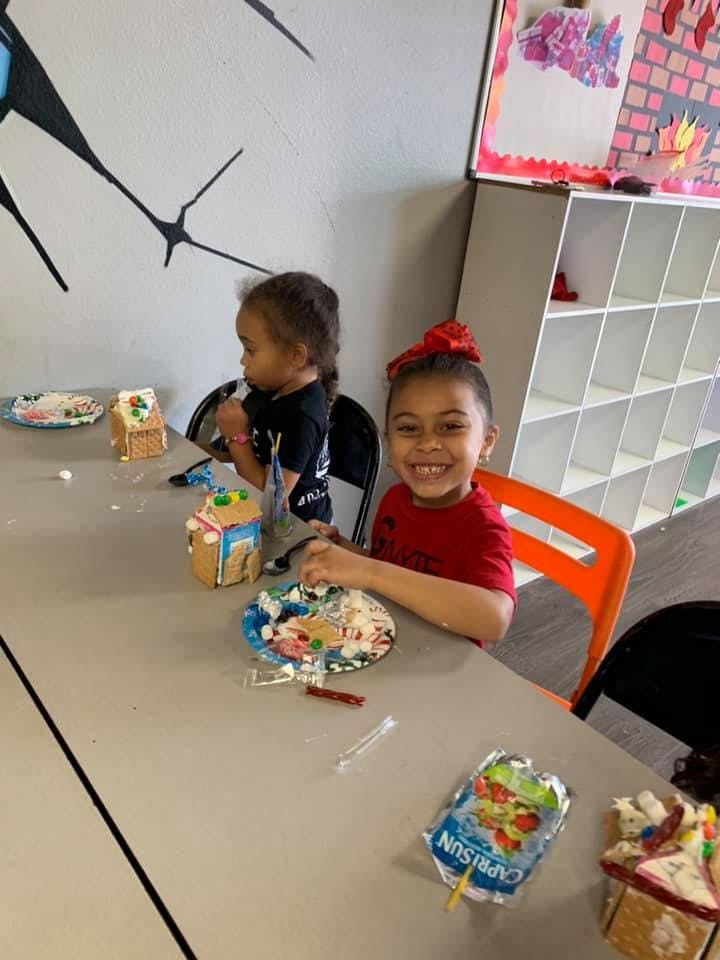 Two children decorating gingerbread houses at a table