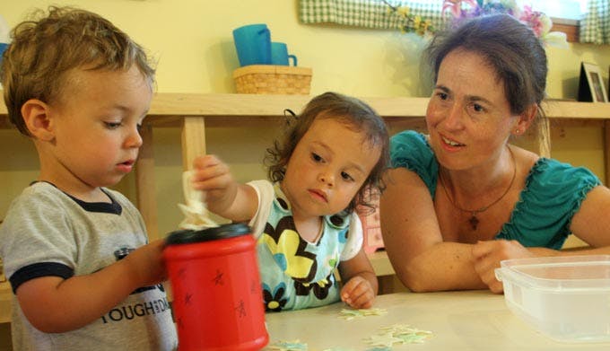 Adult and two children playing with toys at a table