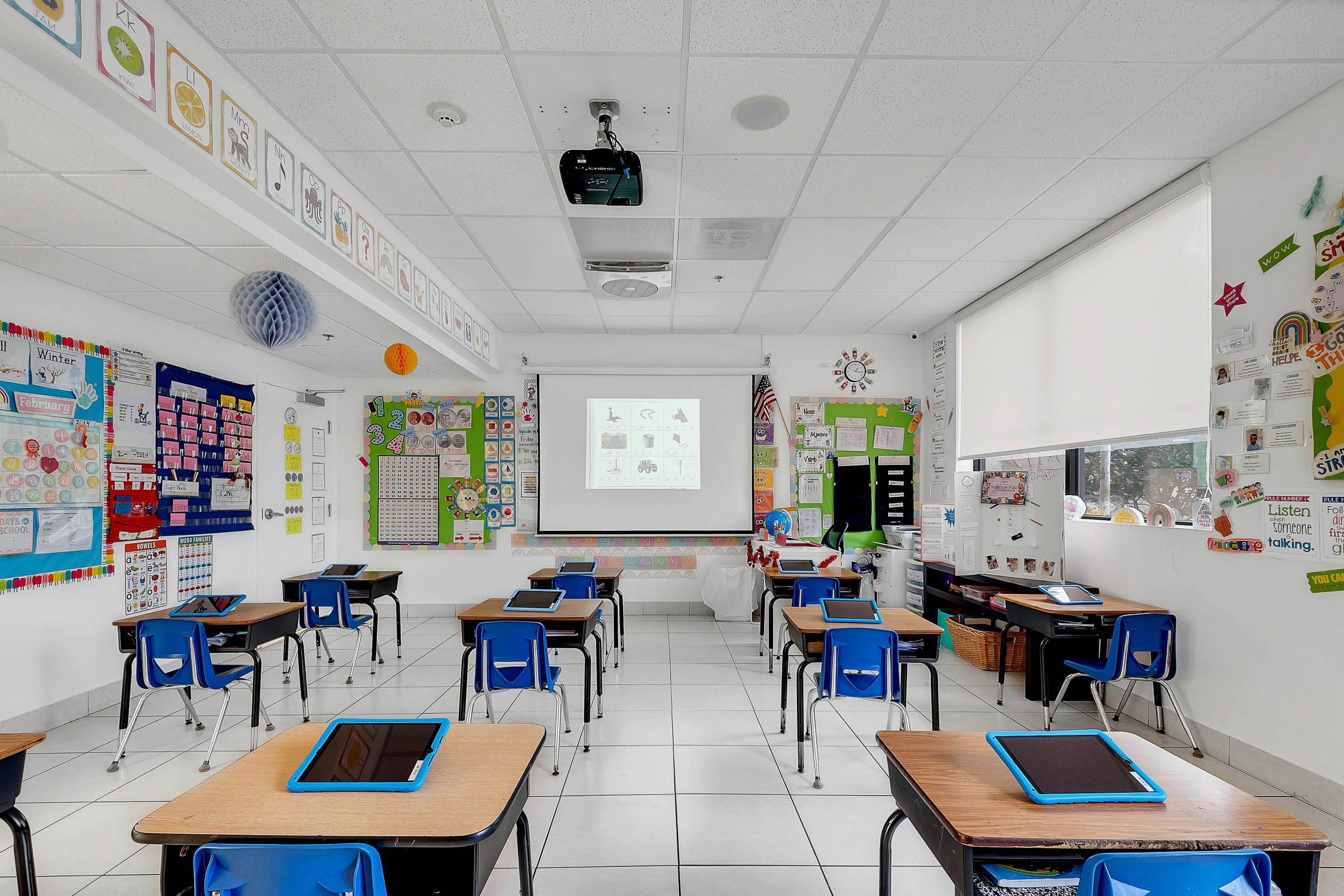 Empty classroom with desks, chairs, and a projector screen