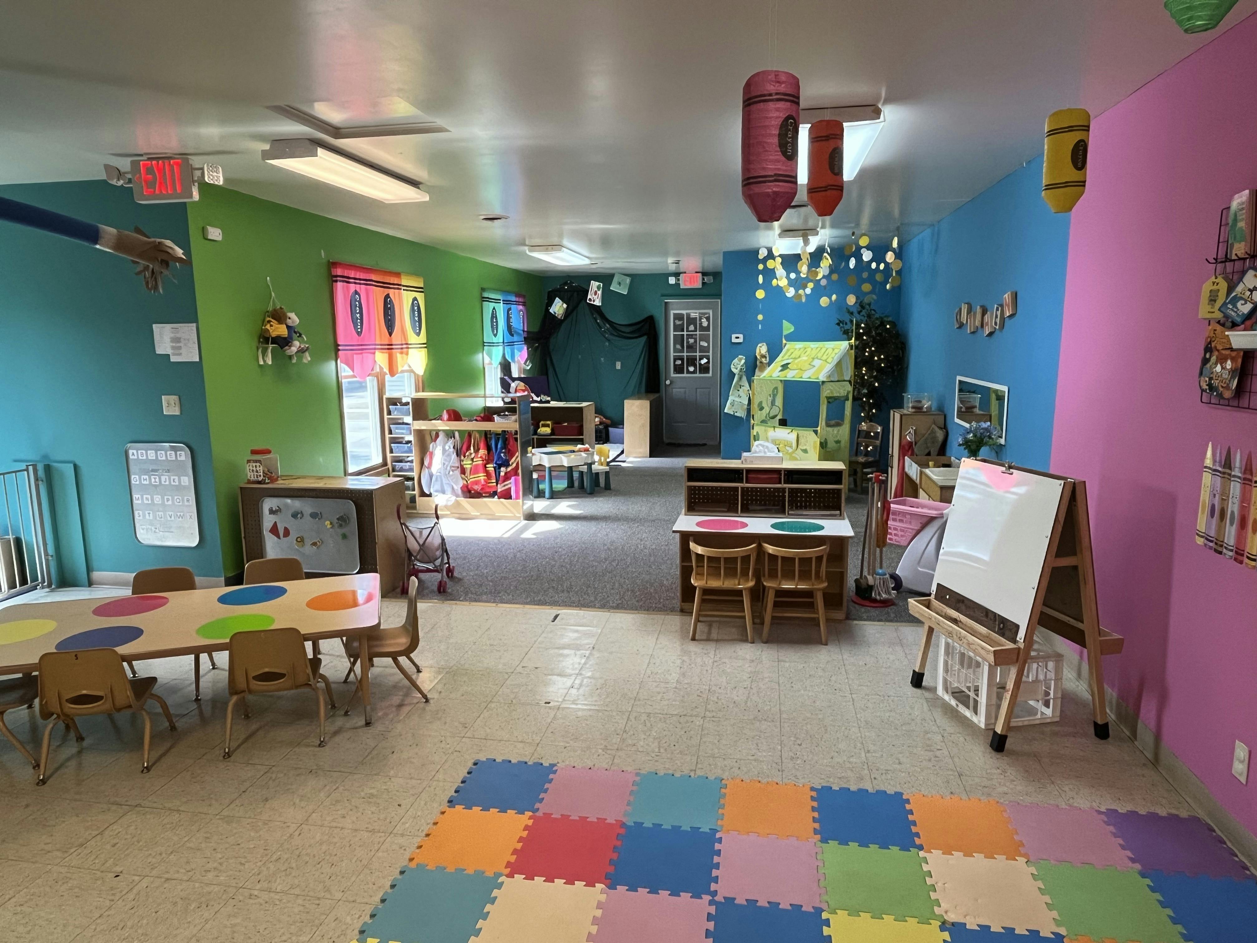Colorful classroom with small tables and chairs, an easel, and play areas