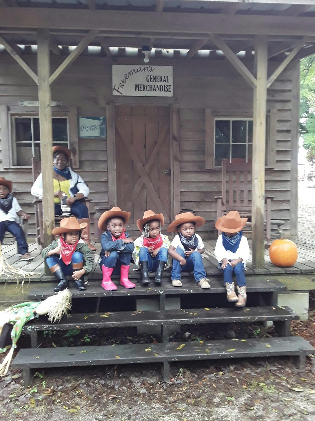 Children in cowboy hats and bandanas sitting on porch steps